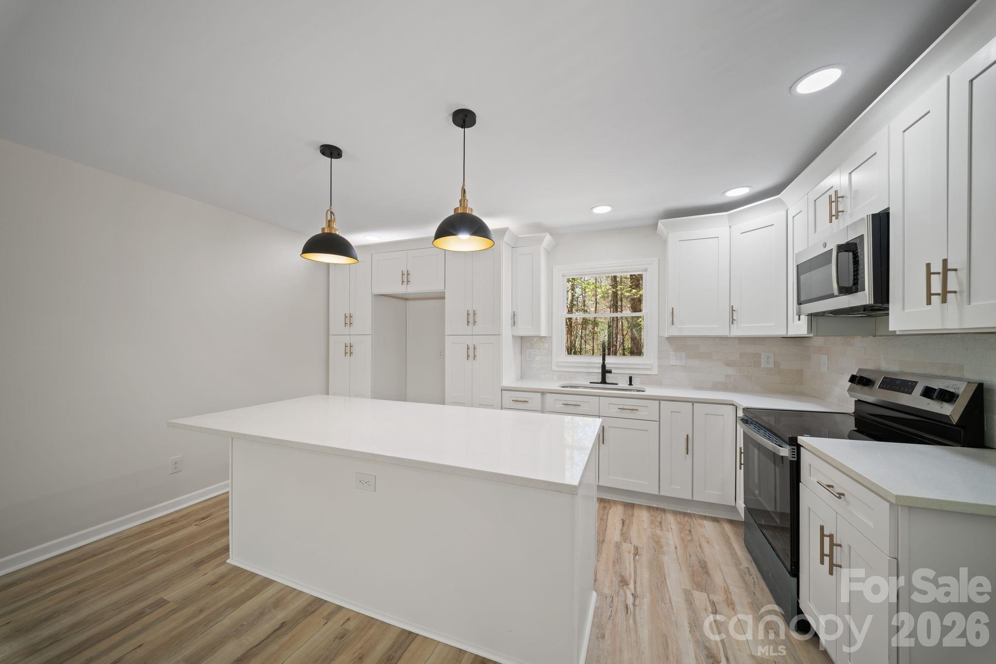 1263 See Off Mountain Road Brevard, NC 28712 - Photo 6 of 21 a large kitchen with stainless steel appliances a large counter top a sink a stove and a refrigerator
