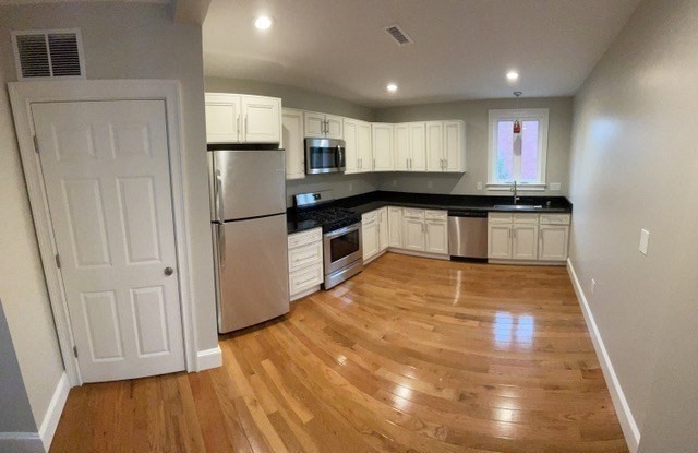 15 Dix Street, Unit 2 Boston, MA 02122 - Photo 3 of 14 a kitchen with stainless steel appliances granite countertop a refrigerator a stove and a wooden floors