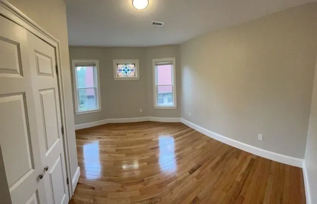 a view of empty room with wooden floor