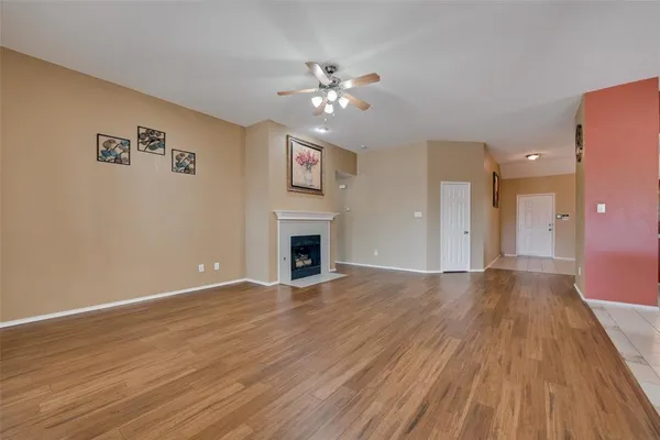 a view of an empty room with wooden floor and a fireplace