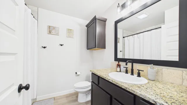 a bathroom with a granite countertop sink mirror vanity and toilet