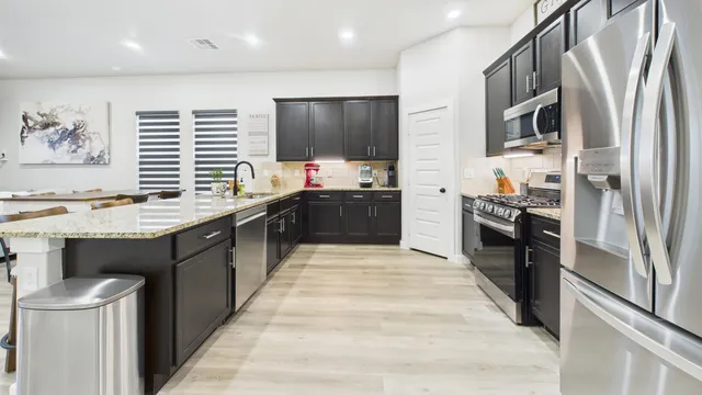 a large kitchen with stainless steel appliances kitchen island granite countertop a stove and a refrigerator