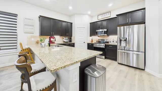 a kitchen with stainless steel appliances granite countertop a refrigerator stove microwave and sink