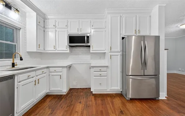 a kitchen with cabinets wooden floor and stainless steel appliances