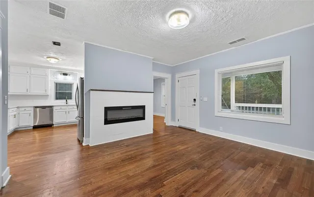 an empty room with kitchen view and a fireplace