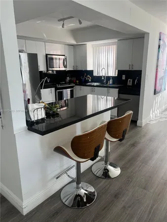 a kitchen with granite countertop a stove a sink dishwasher and a microwave with wooden floor