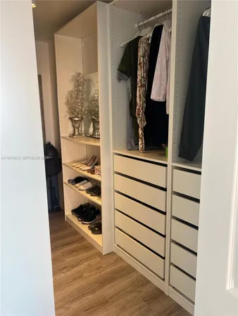 a view of walk in closet with clothes and shoes