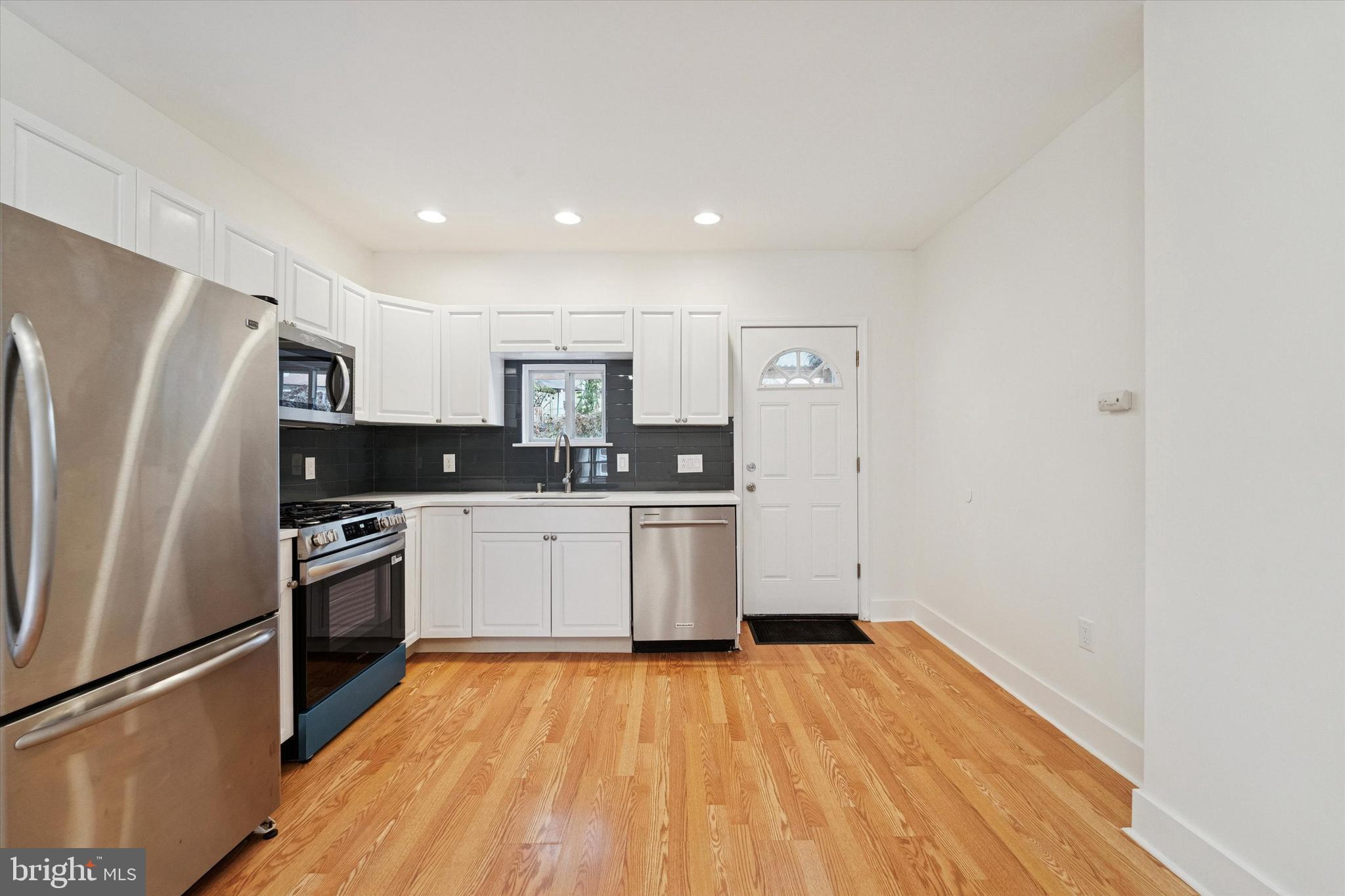2353 East Huntingdon Street Philadelphia, PA 19125 - Photo 23 of 42 a kitchen with granite countertop a refrigerator oven a sink dishwasher and white cabinets with wooden floor