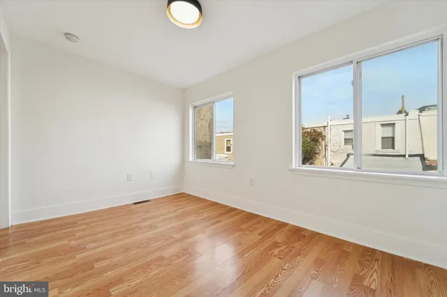 a view of empty room with wooden floor and window