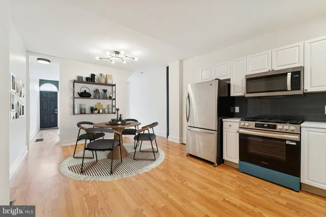 a kitchen with stainless steel appliances a stove a refrigerator island cabinets and wooden floor