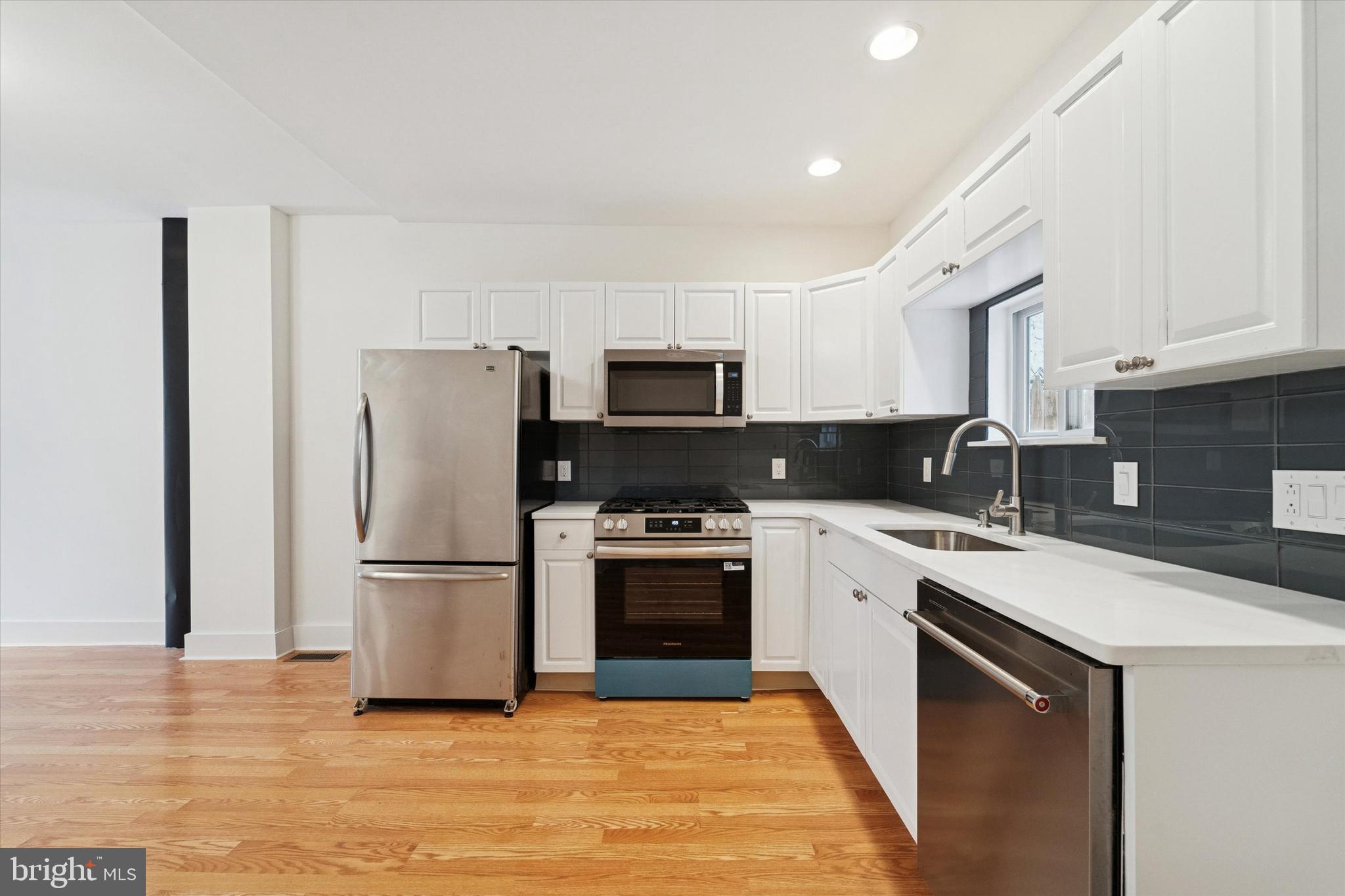 2353 East Huntingdon Street Philadelphia, PA 19125 - Photo 8 of 42 a kitchen with a sink a microwave a refrigerator and cabinets