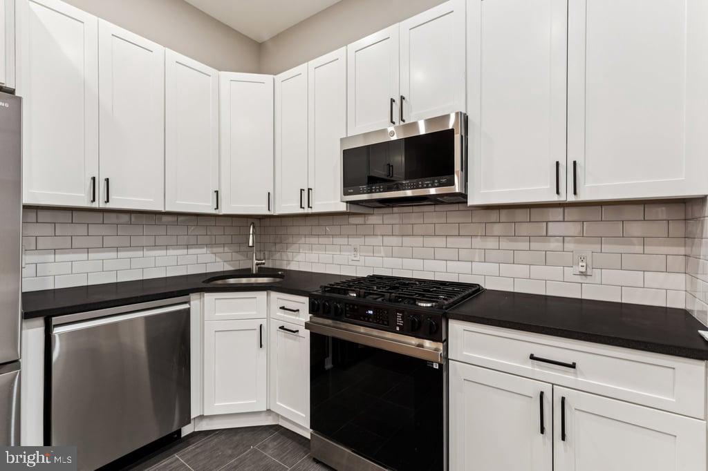 2101 Spruce Street, Unit 2R Philadelphia, PA 19103 - Photo 13 of 28 a kitchen with white cabinets and black appliances