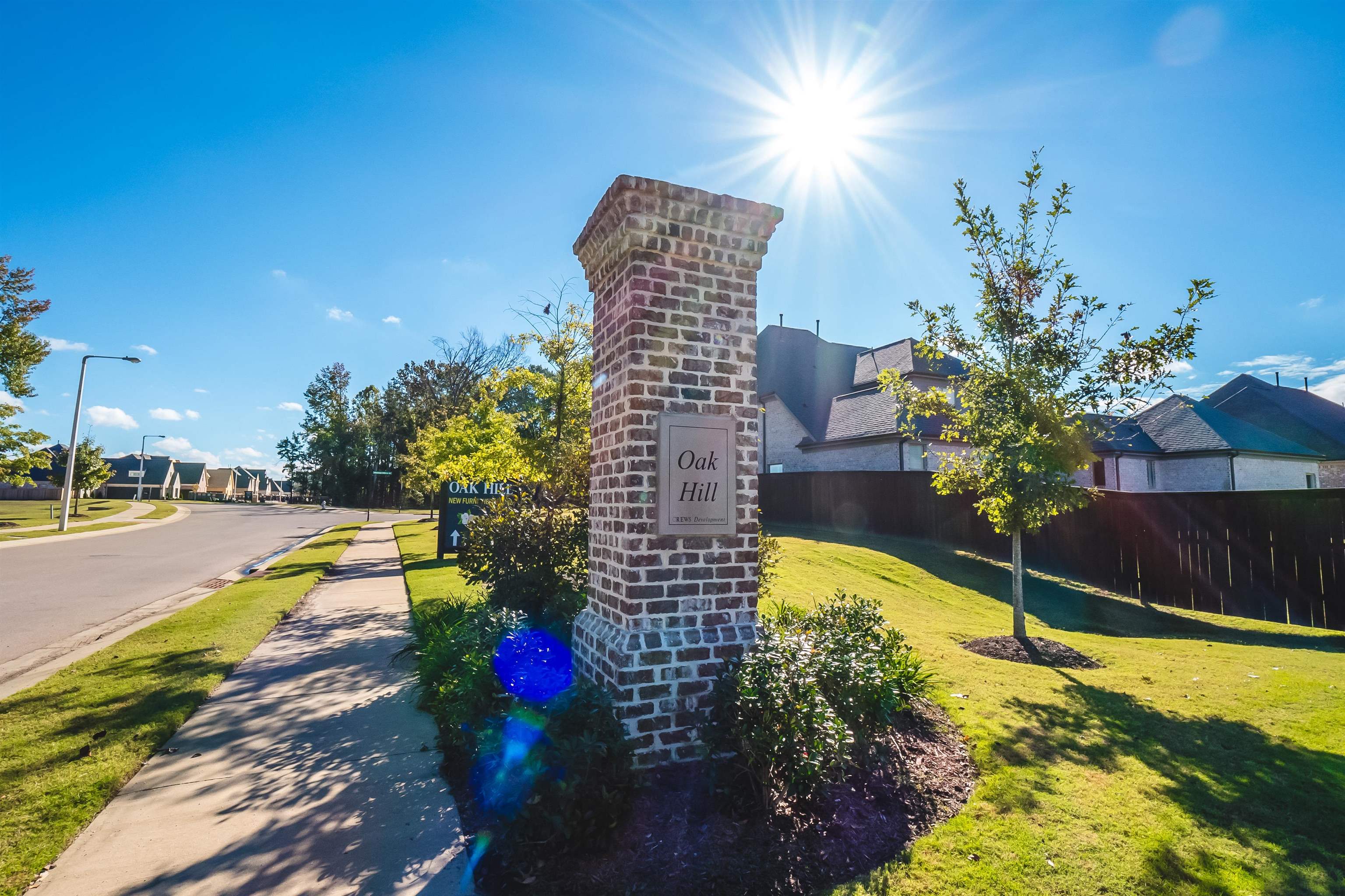 284 Keisie Lane Collierville, TN 38017 - Photo 29 of 34 Brick column entrance featuring a raised plaque, manicured landscaping, paved sidewalks, and a street lamp