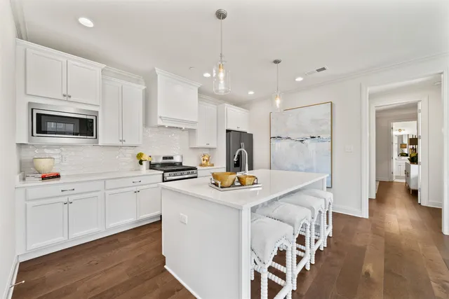 a kitchen with stainless steel appliances granite countertop a sink a stove a refrigerator and white cabinets with wooden floor