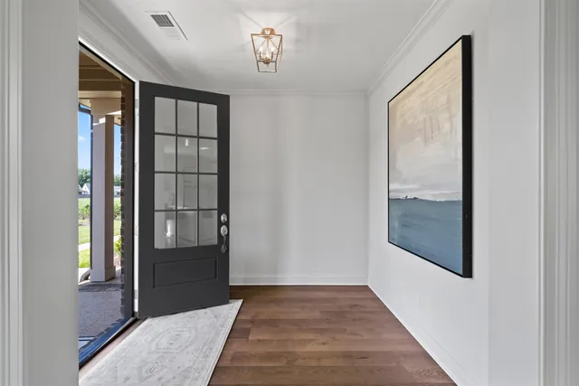 a view of a hallway with wooden floor and a chandelier