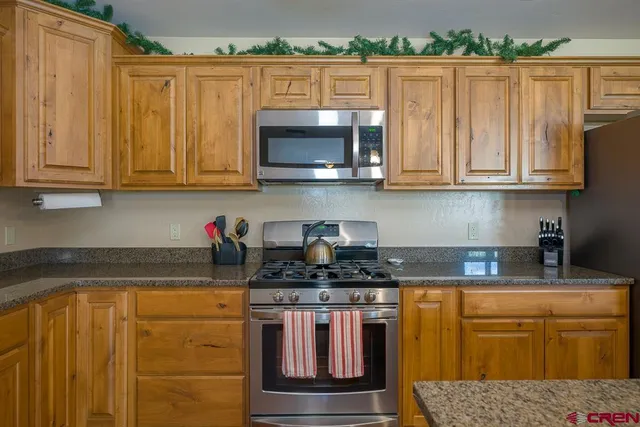 a kitchen with stainless steel appliances granite countertop a stove a sink and a microwave