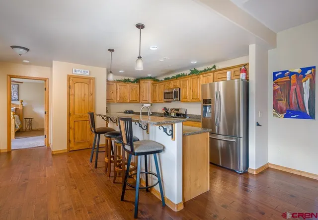 a kitchen with stainless steel appliances a refrigerator a stove a sink dishwasher and a dining table with wooden floor