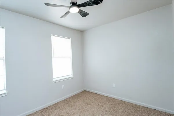 an empty room with a window and a fan
