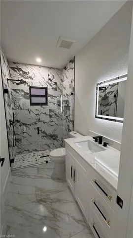 a bathroom with a sink a toilet a mirror and shower