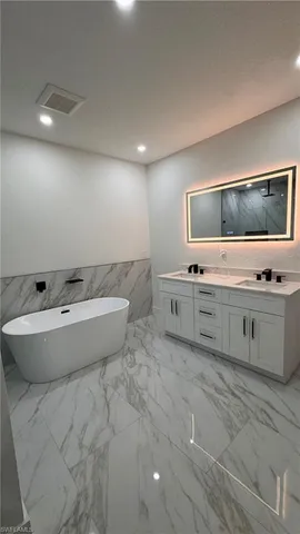 a view of a spacious bathroom with stainless steel appliances double vanity sink and mirror