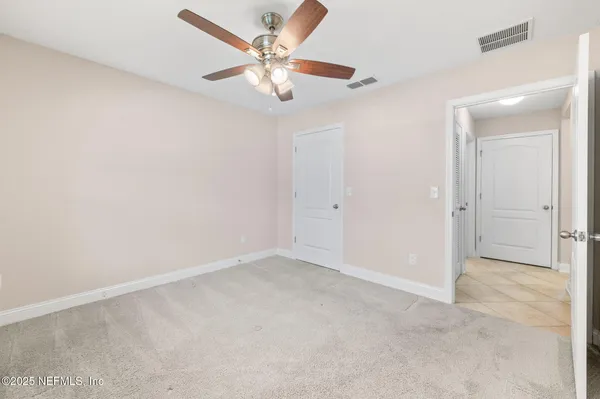 an empty room with a chandelier fan and windows