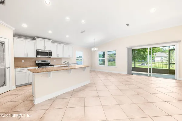 a large white kitchen with a stove a sink a microwave and a counter top space