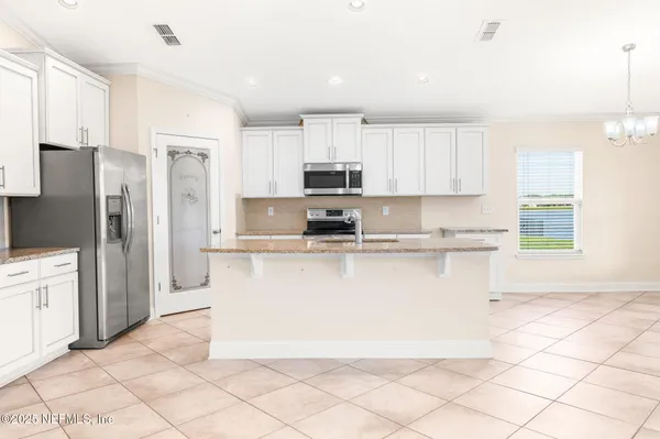 a kitchen with stainless steel appliances granite countertop a refrigerator a stove a sink and white cabinets