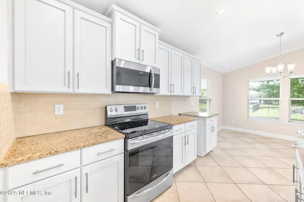 a kitchen with granite countertop white cabinets a sink dishwasher and a stove with wooden floor