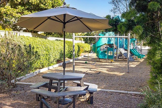 a backyard view of a house with table and chairs under an umbrella