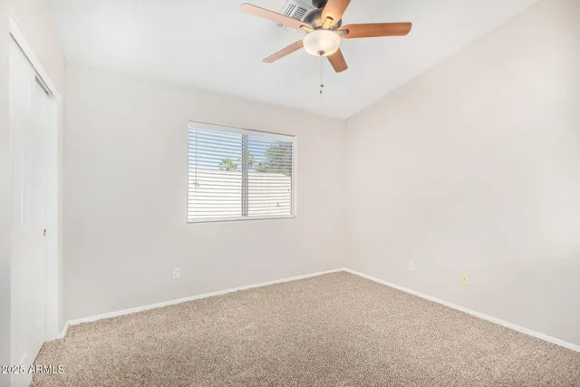 an empty room with a window and a fan