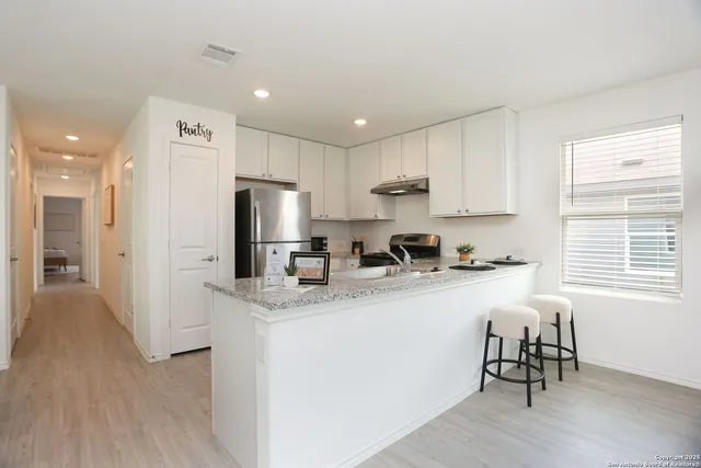 a kitchen with stainless steel appliances granite countertop a refrigerator a sink dishwasher a stove and a refrigerator with wooden floor