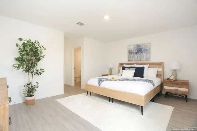 a bedroom with a large bed and a potted plant