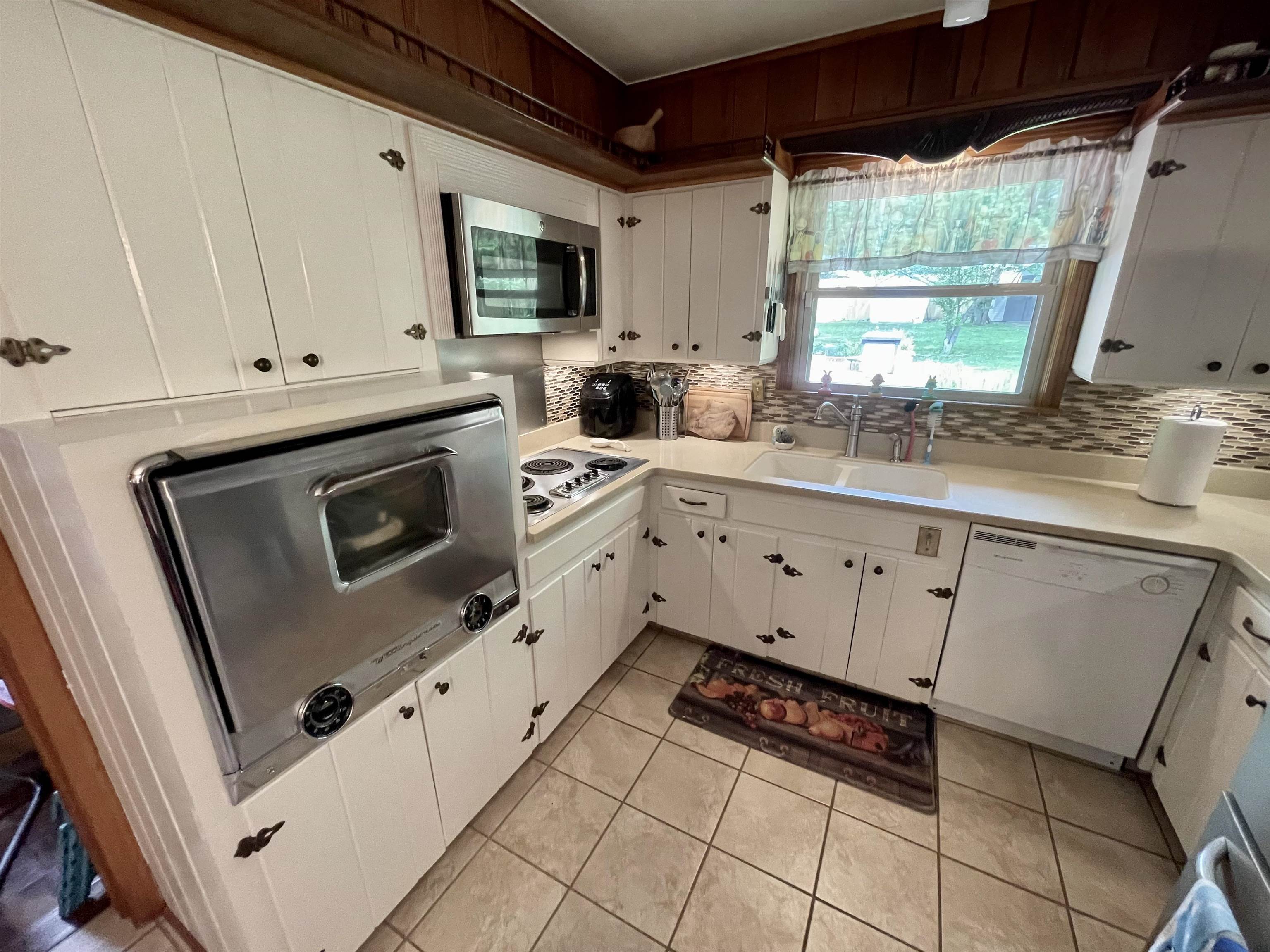 5200 Walnut Grove Road Memphis, TN 38117 - Photo 6 of 24 a kitchen with white cabinets a sink dishwasher and a stove with wooden floor