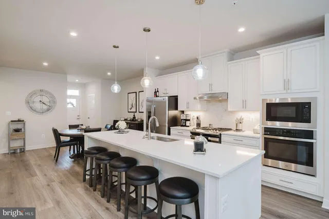 a kitchen with stainless steel appliances a table chairs and a refrigerator