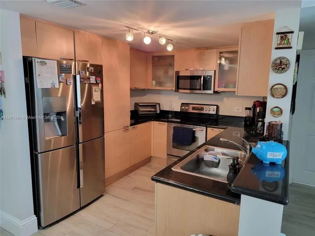 a kitchen with stainless steel appliances granite countertop a refrigerator stove top oven a sink and dishwasher