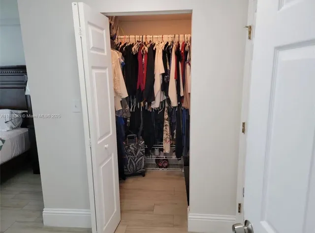 a view of walk in closet with clothes and shoes