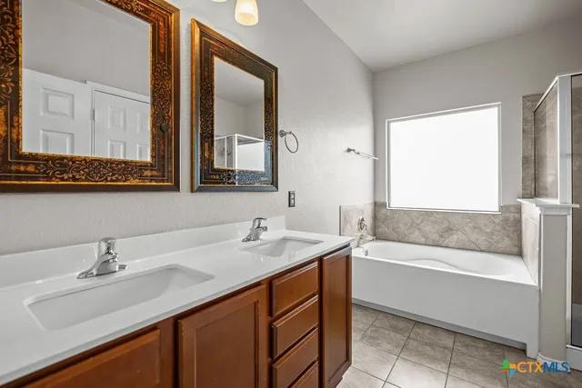 a bathroom with a sink double vanity granite tub shower and a mirror