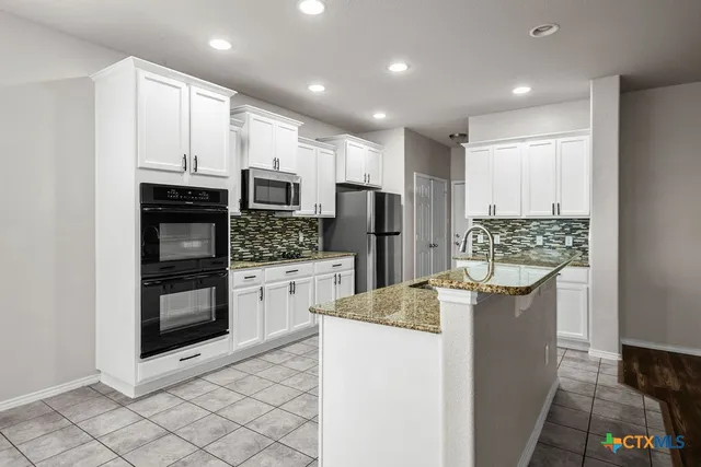 a kitchen with stainless steel appliances kitchen island granite countertop a refrigerator and a stove top oven