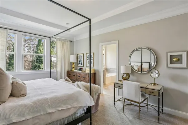 a bedroom with a bed a table and large windows