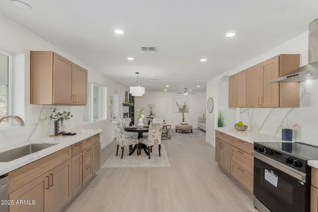 a large kitchen with stainless steel appliances a sink a counter top space and cabinets