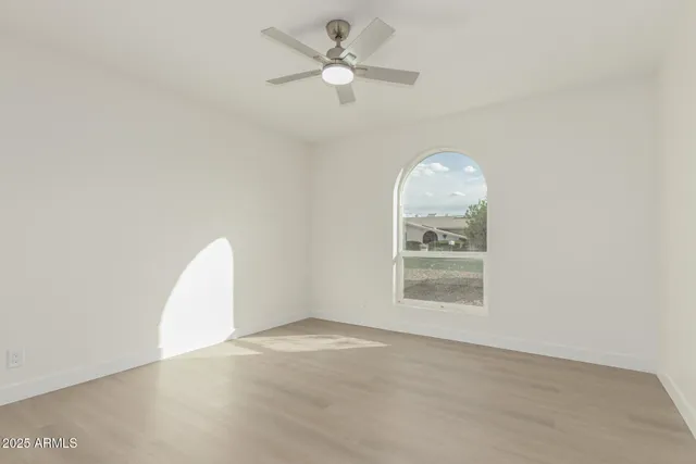 an empty room with a window and a chandelier fan