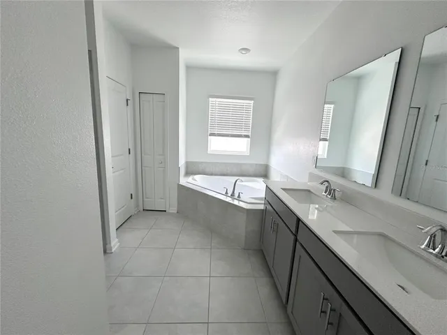 a bathroom with a granite countertop bathtub sink vanity and mirror