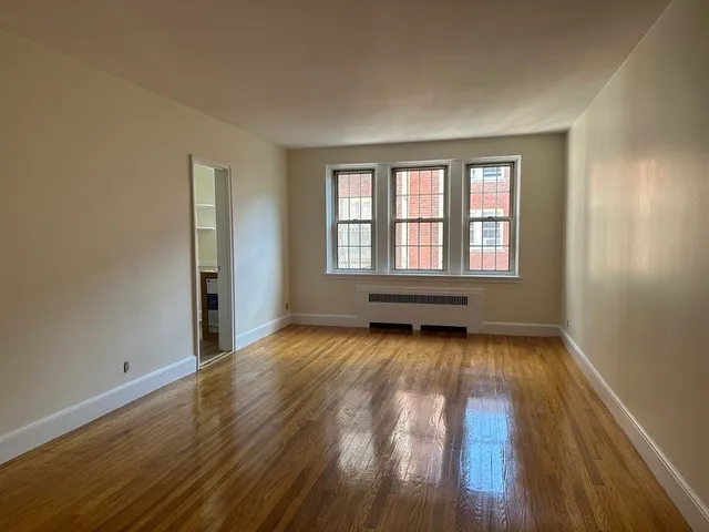 a view of an empty room with wooden floor and window
