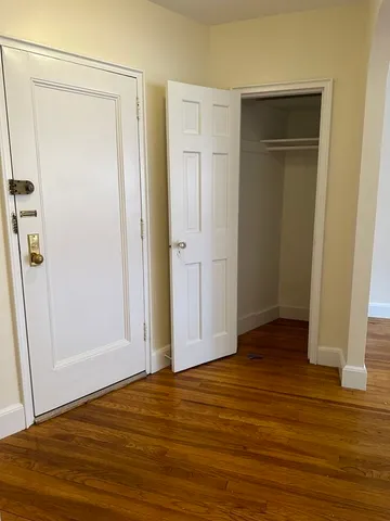 an empty room with wooden floor and closet area