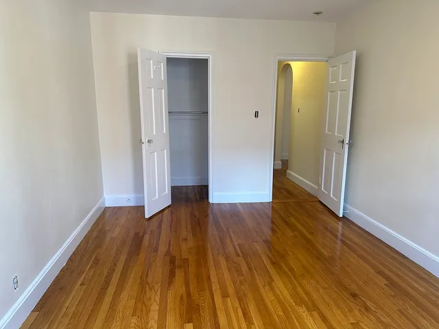 an empty room with wooden floor and entrance