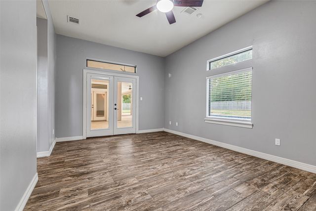 a view of an empty room with window and wooden floor