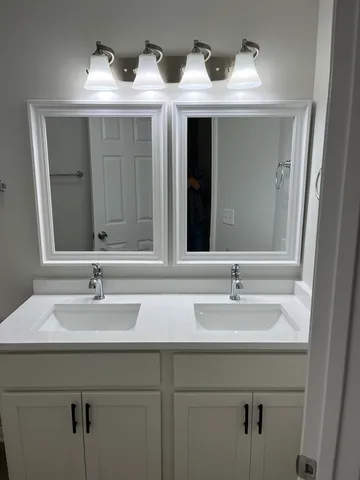 a bathroom with double vanity sinks and a mirror