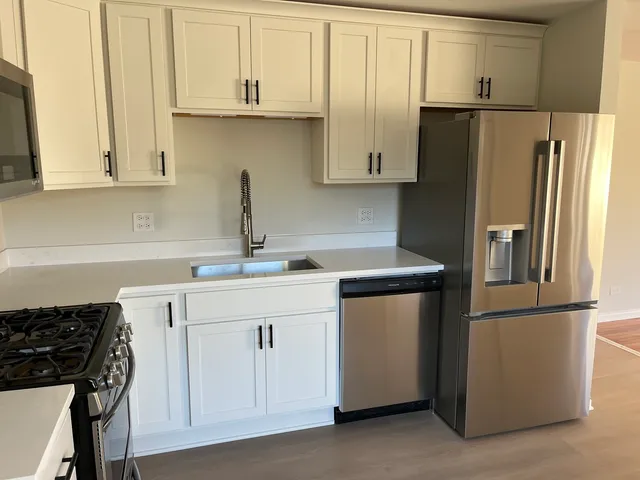 a kitchen with stainless steel appliances granite countertop a refrigerator sink and white cabinets
