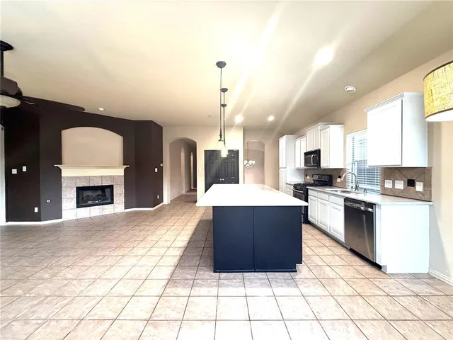 a large kitchen with a stove a sink dishwasher and a fireplace with wooden floor