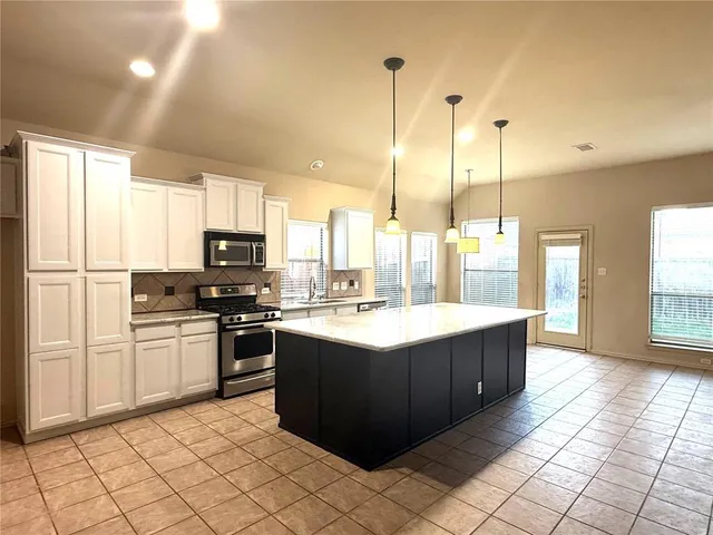 a kitchen with stainless steel appliances granite countertop a sink counter space and a view of living room